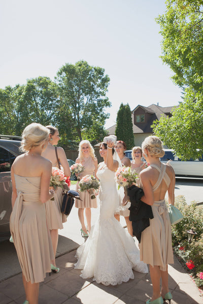 Bride surrounded by six bridesmaids, throwing the bouquet at garden-themed wedding 