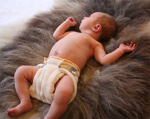 organic prefold cloth diaper pinnned on a newborn baby