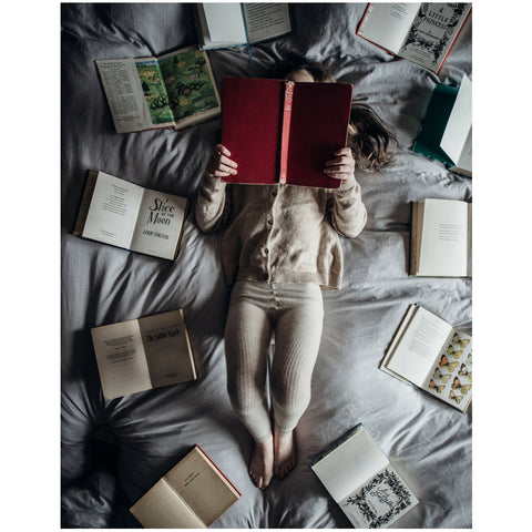 Child reading books laying on the bed