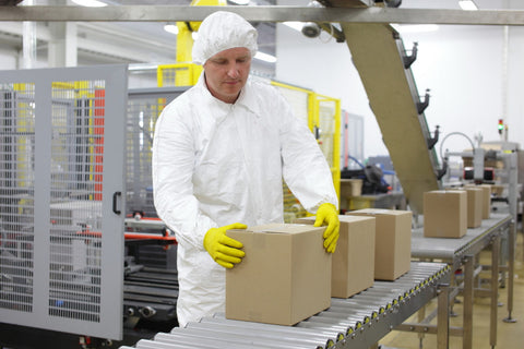 worker in white apron dealing with boxes at packing line in factory