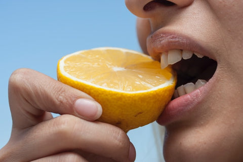 woman biting into half a lemon