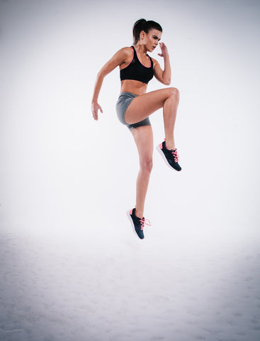 Woman jumping high off the ground with knees extended