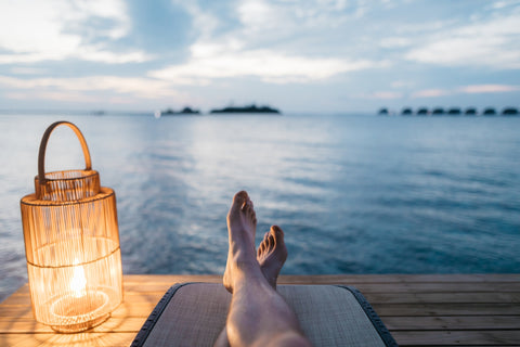 A person relaxing beside a lamp and a body of water