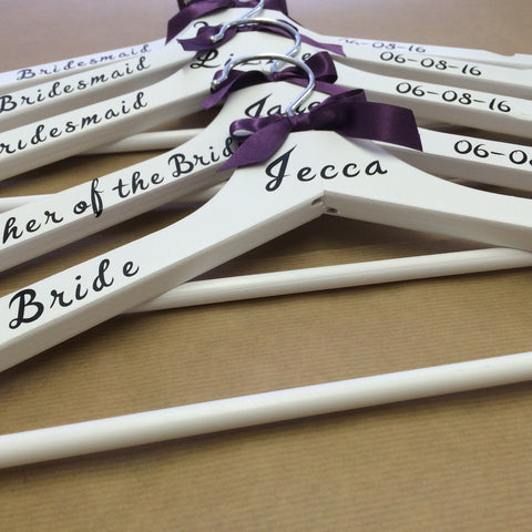 4 white hangers with personalised wording on and a little purple bow