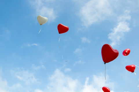 A collelction of red and white heart shaped balloons in the sky.