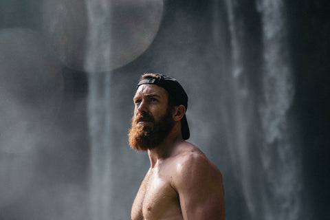 A man with a beard and a hat outdoors.