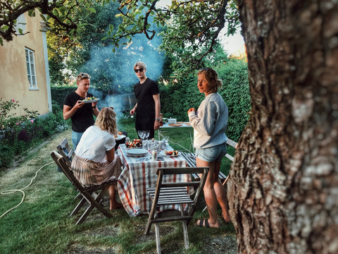 A group of people having a cookout outside in a yard.
