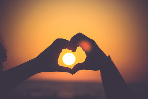 The sun and a heart made with two hands.