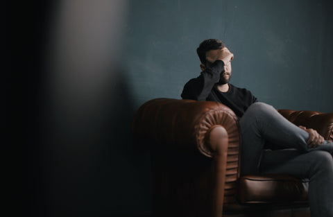 A man with a headache on a couch.