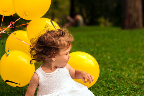 A happy infant with yellow balloons.