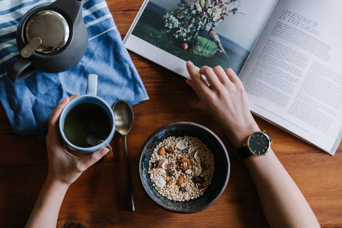 A table with tea and magazine and breakfast.