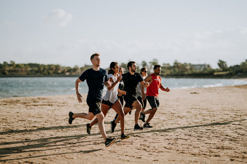 A group of people running on the beach.