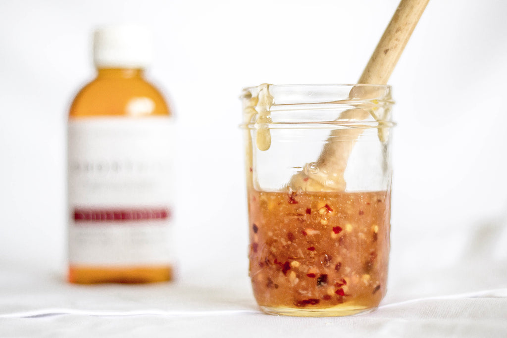 Image showing ShortHive habanero chilli sauce recipe using ShortHive (hot) honey. Sauce in glass jar with honey stick and bottle blurred in the background.