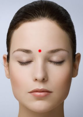 woman's face eyes closed with red dot in the middle of her forehead