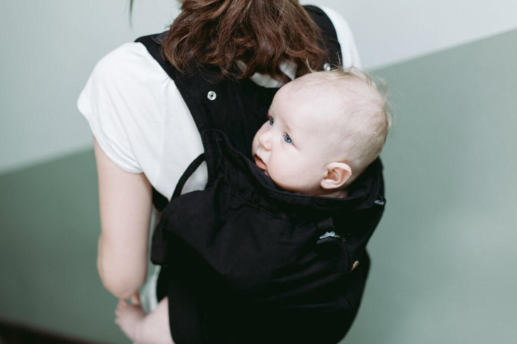 Young mother carrying baby on her back in Weego Baby Carrier