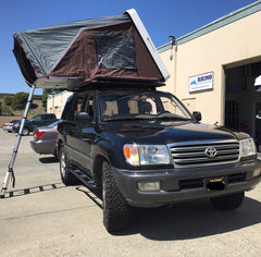 black 100 Series Toyota Land Cruiser with Rhino Rack Backbone Pioneer Platform Rack System and white iKamper Skycamp 4x v2 Roof Top Tent