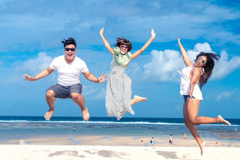 three excited friends jumping on the beach