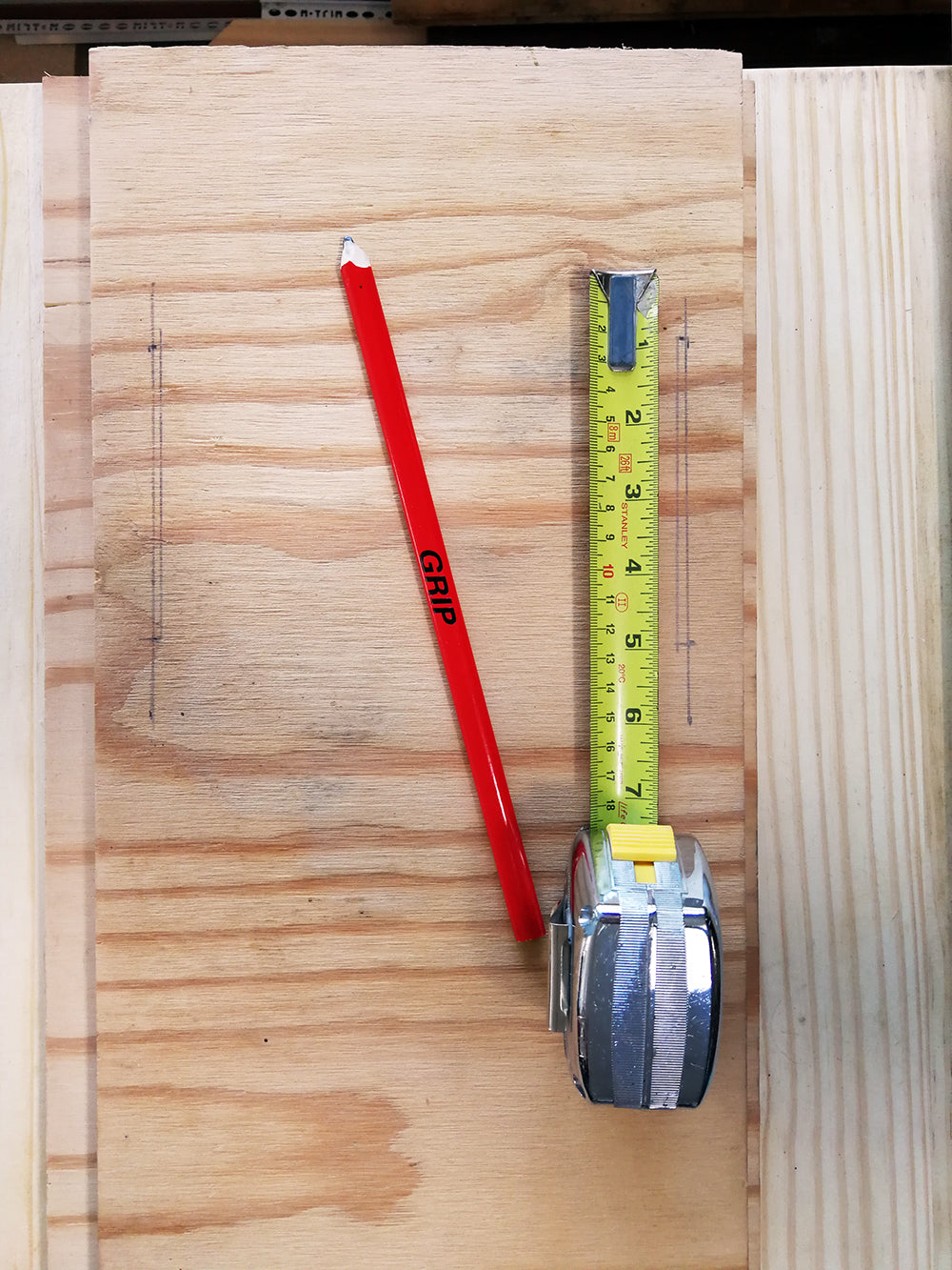 measuring tape and pencil on plywood for shelving tutorial