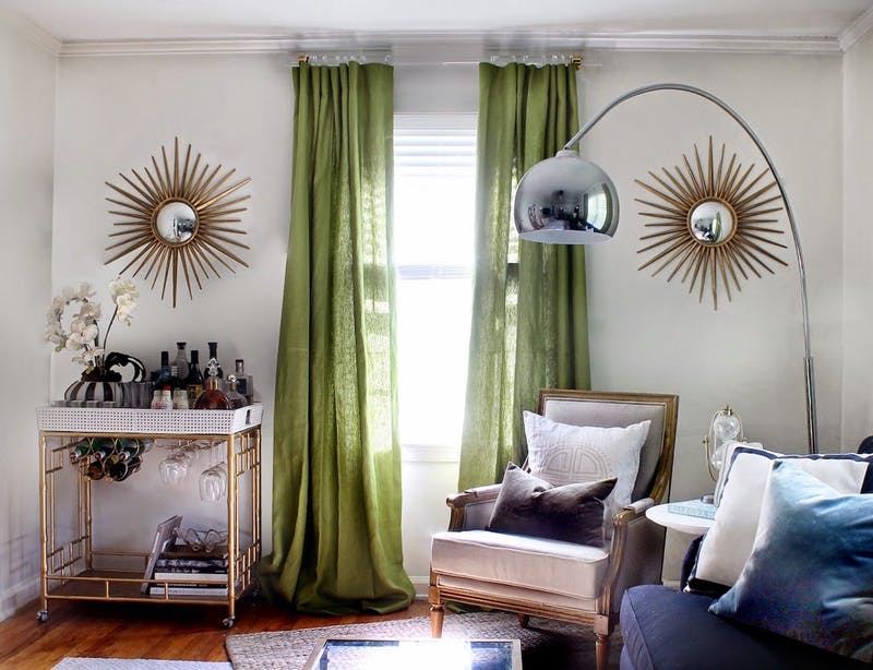 eclectic room with gold sun mirrors green curtains and acrylic curtain rod