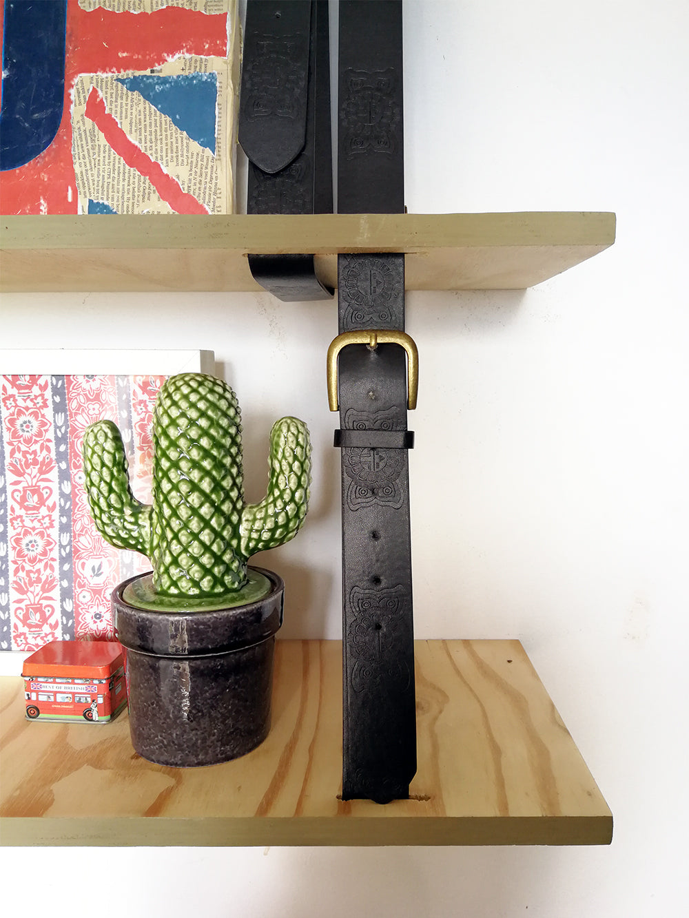 close up of hanging shelf in home office with glass cactus and belt detail