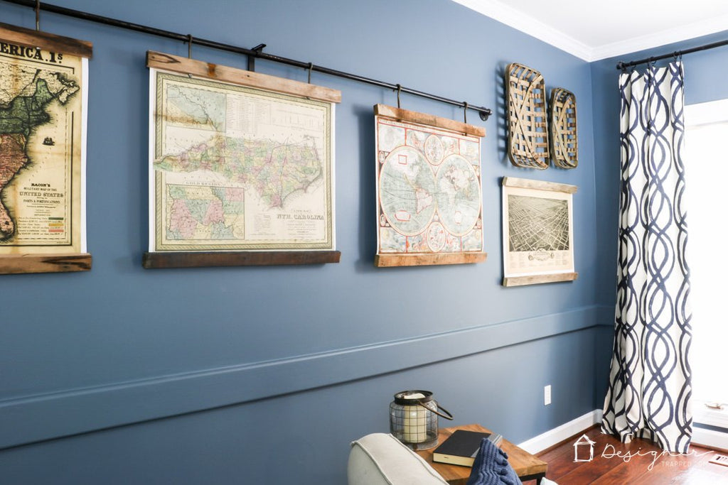 printed maps hanging from a curtain rod against a blue wall