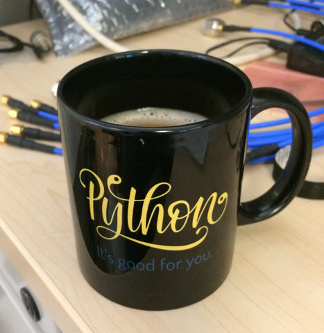 "Python it's good for you" mug in black, filled with coffee