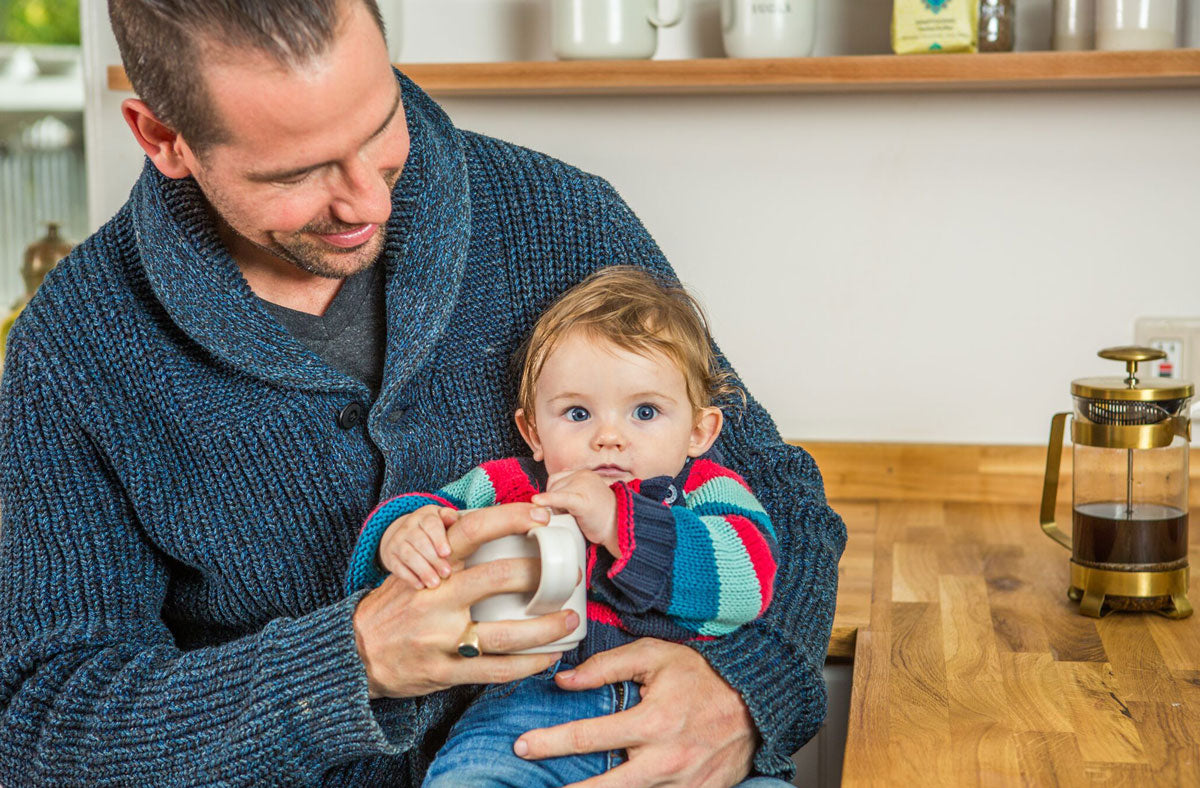 Dad holding child while drinking coffee