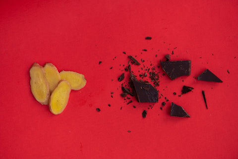 Ginger slices and chocolate fragments on red background