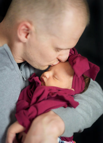 father kissing newborn baby