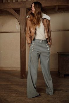 Woman wearing grey sailor pants with brown leather jacket and white shirt.