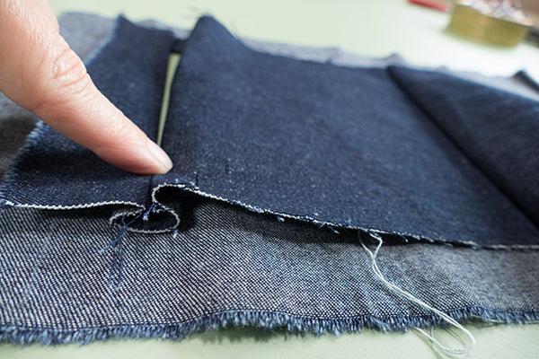 Fold up the bottom of the welt pocket, making a pleat, covering the bottom half of the pocket opening.