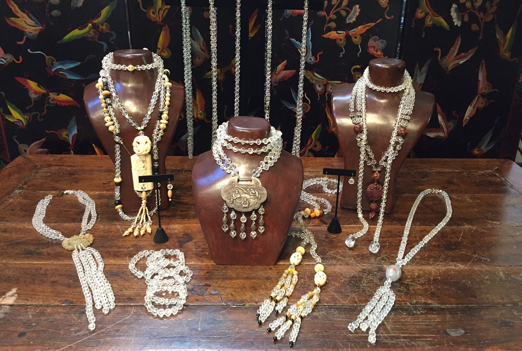 photo of several custom designed necklaces from Sunya Currie adorning a table and wooden busts