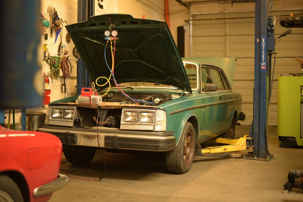 Volvo 240 on lift with hood up, undergoing air conditioning service