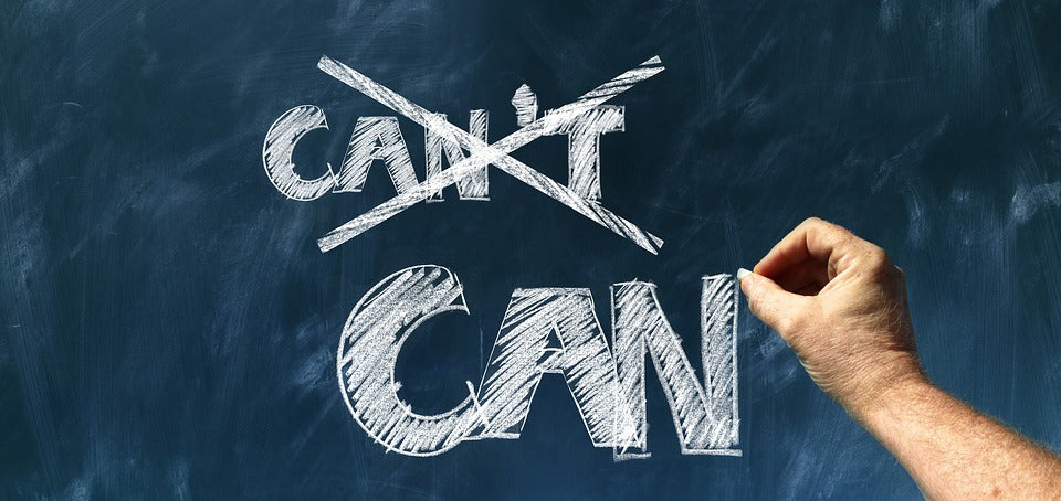 Positive thinking - a blackboard with a hand writing in bold white chalk letters “can” and “can’t” crossed out.