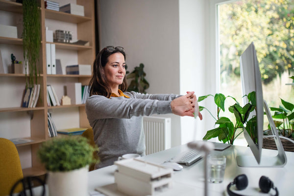 Frau streckt sich im Home-Office