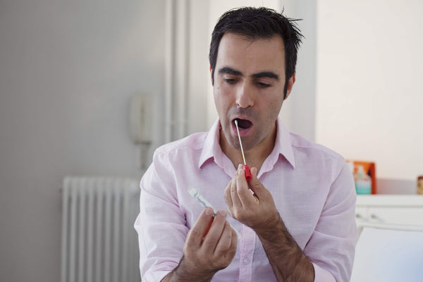 Homme se testant lui-même au virus SARS-CoV-2 par test salivaire