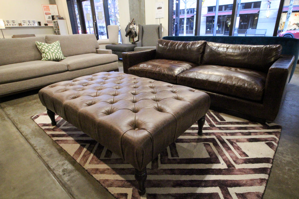 Brown leather tufted ottoman with turned legs