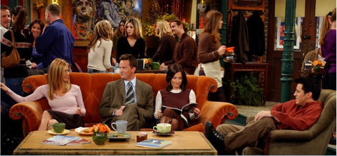 Friends characters Rachel, Chandler and Monica sitting on an the orange sofa at Central Perk in an episode of Friends. 