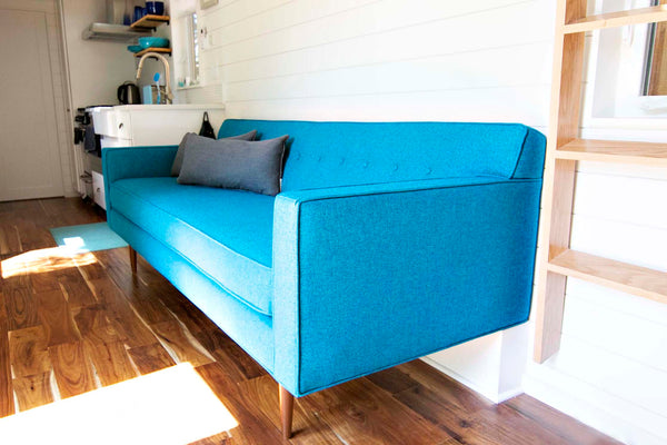 This custom Sterling sofa two legs in the front and the back side of the couch sits atop the tiny house's wheel well 