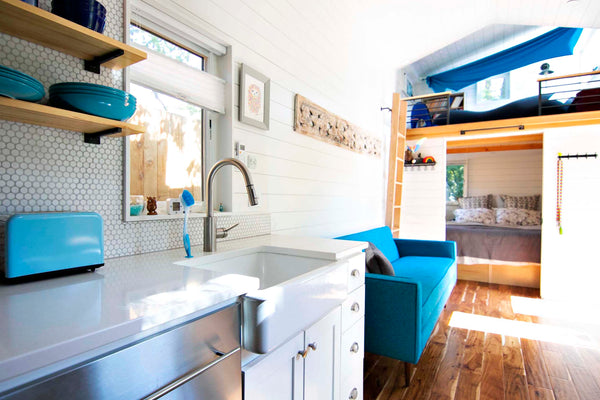 Teal accents create a pop of color in this modern farm house style tiny home on wheels.