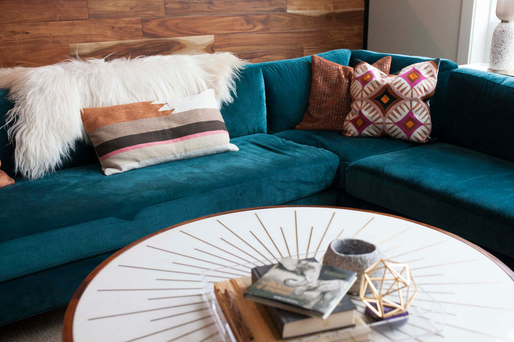Adding throw pillows and a sheep skin rug adds texture to the teal blue velvet Charlie Sectional from Perch Furniture.