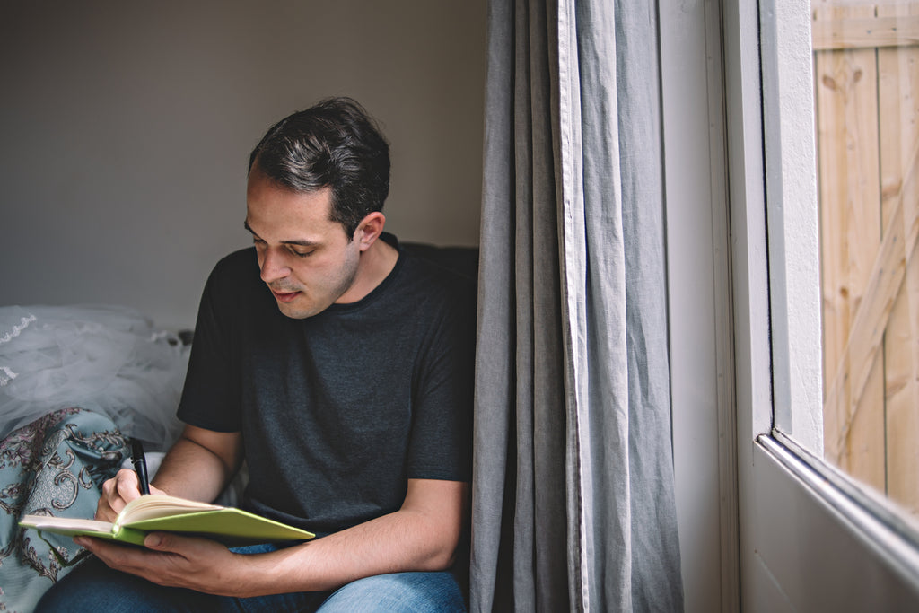 man writing in journal