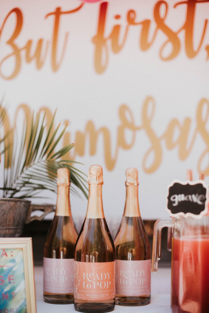 a pink and orange mimosa bar with Ready to Pop for the guest of honor