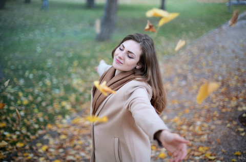 Woman enjoying the leaves falling in Autumn