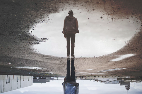 man and his reflection in a puddle