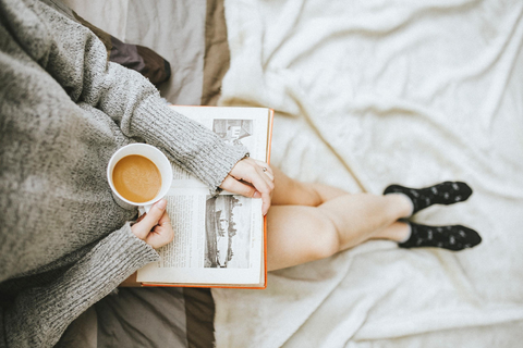 Woman lounging, drinking tea and reading a book