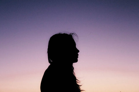 Woman's profile with a sunset sky behind her