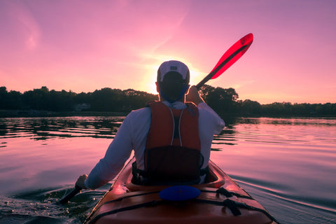 Person riding a boat down a river at sunset