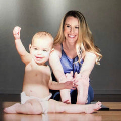 Woman does a forward fold with her baby in front of her Photo by Crystal Sagan