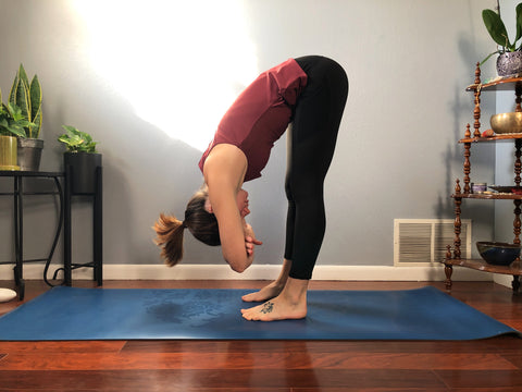 girl on yoga mat does a forward fold